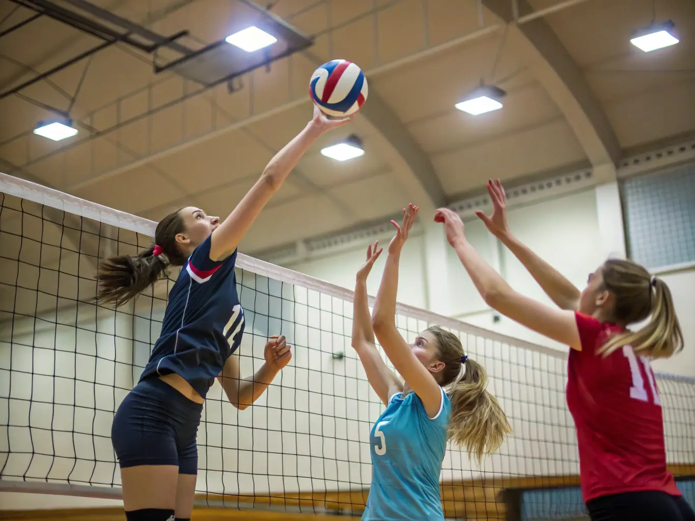 A dynamic shot of a volleyball team in action, focusing on the teamwork and coordination involved in a game. Players are diving, setting, and spiking the ball, showcasing the energy and excitement of volleyball.
